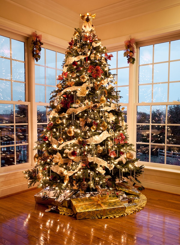 Christmas tree with presents and lights reflecting in windows around the tree in modern home